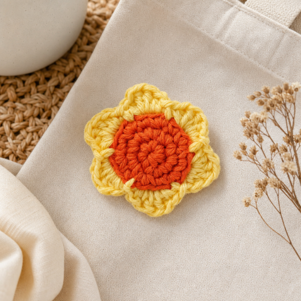 Prendedor con flor tejida a mano en colores anaranjado y amarillo